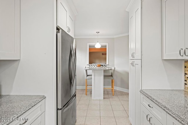 kitchen featuring ornamental molding, white cabinetry, light stone countertops, and stainless steel refrigerator