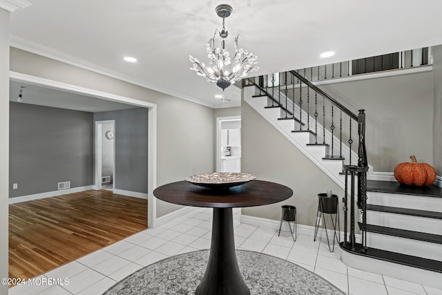 foyer entrance with ornamental molding, a chandelier, and light wood-type flooring