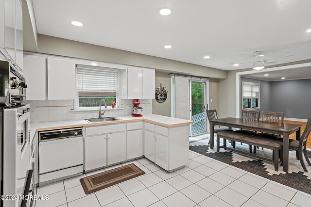 kitchen featuring white appliances, tasteful backsplash, sink, kitchen peninsula, and white cabinetry