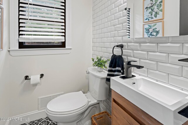 bathroom with toilet, tile patterned flooring, vanity, and backsplash