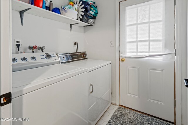 clothes washing area featuring light tile patterned flooring and washing machine and dryer