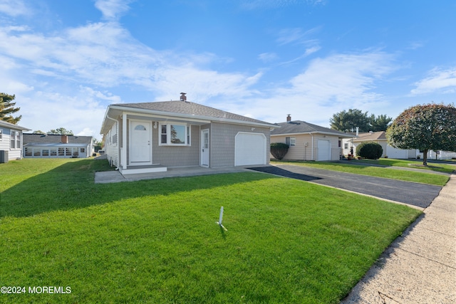 view of front of property featuring a garage, a front lawn, and central AC unit