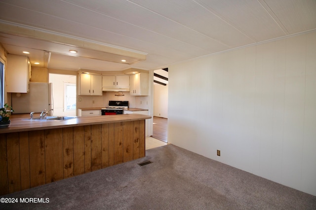 kitchen featuring light carpet, kitchen peninsula, white cabinets, white range with gas cooktop, and fridge