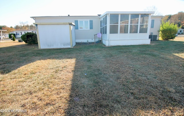 back of property featuring a yard, a sunroom, and central AC unit