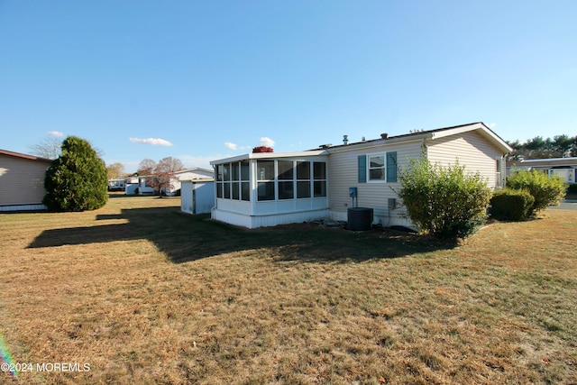 rear view of house with central air condition unit, a yard, and a sunroom