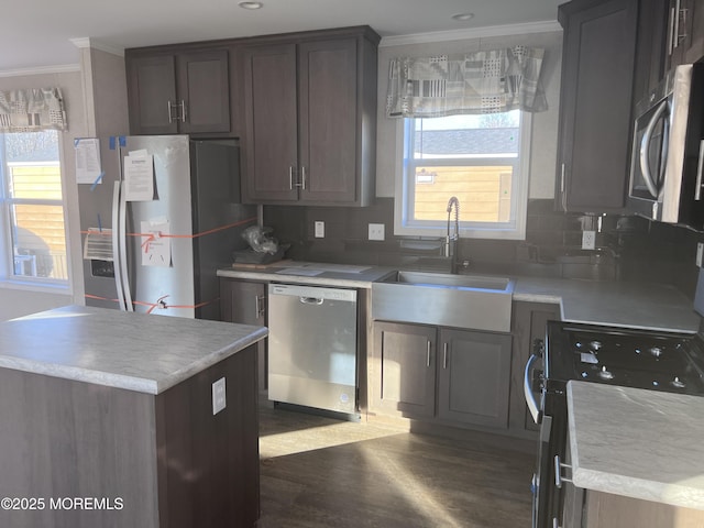 kitchen featuring sink, stainless steel appliances, a kitchen island, dark hardwood / wood-style flooring, and decorative backsplash