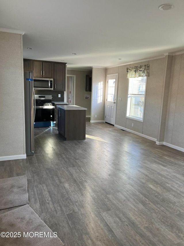 kitchen with appliances with stainless steel finishes, hardwood / wood-style flooring, ornamental molding, a center island, and dark brown cabinetry