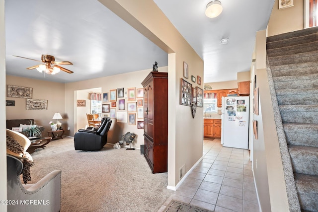 interior space with light tile patterned flooring, ceiling fan, light carpet, and stairs