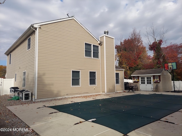 back of property featuring a patio area, a storage shed, and a covered pool