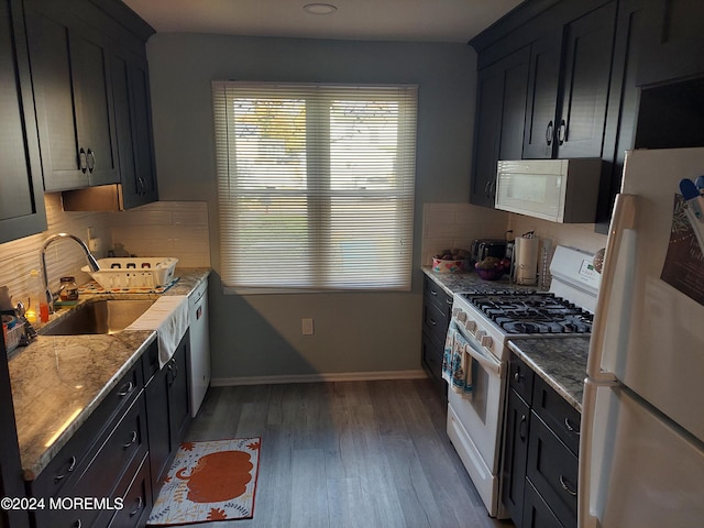 kitchen featuring dark wood-type flooring, sink, light stone countertops, white appliances, and tasteful backsplash