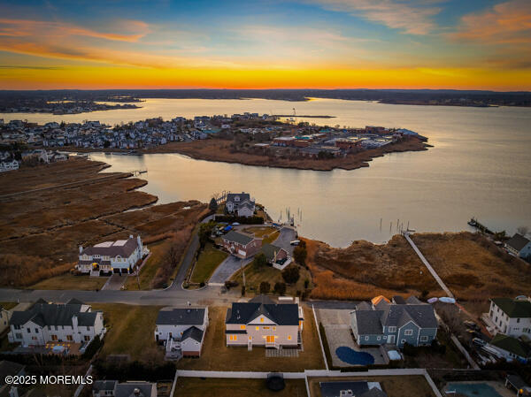 aerial view at dusk featuring a water view and a residential view