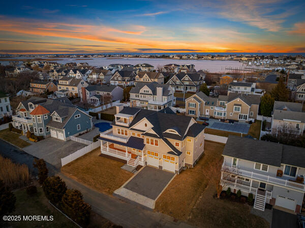 aerial view at dusk featuring a water view and a residential view