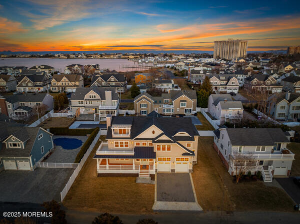 aerial view at dusk featuring a water view and a residential view