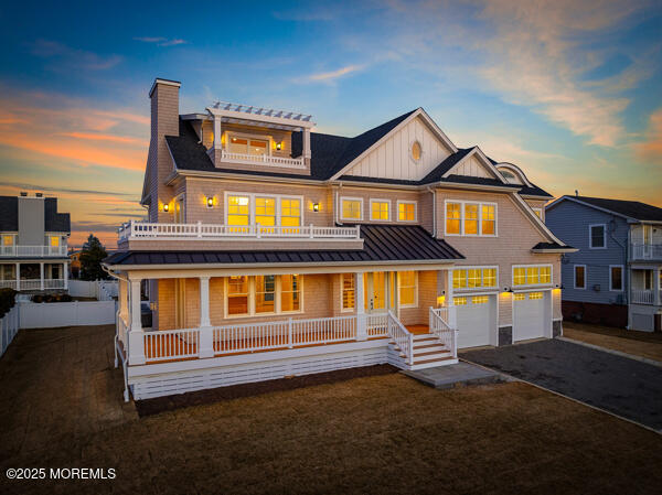 view of front facade with a porch, board and batten siding, a standing seam roof, a balcony, and driveway