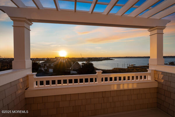 patio terrace at dusk with a water view and a pergola