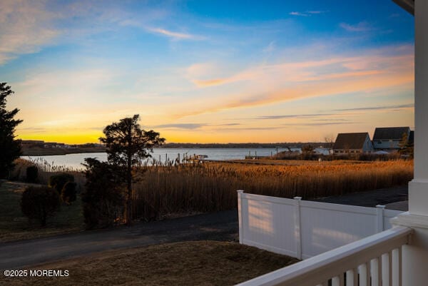 yard at dusk with a water view and fence