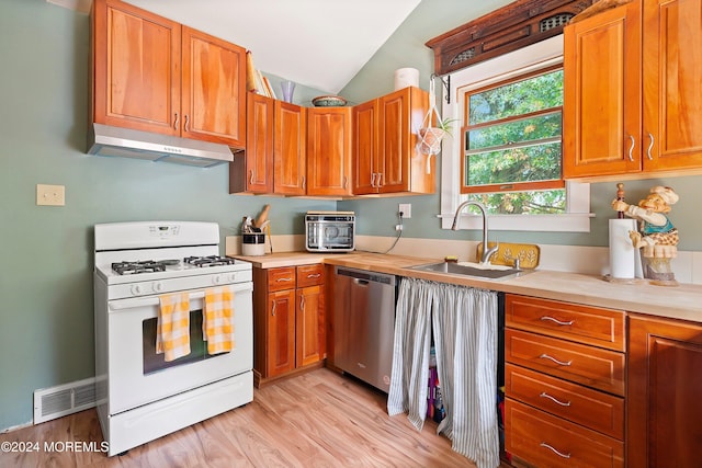 kitchen featuring stainless steel dishwasher, light wood-type flooring, vaulted ceiling, gas range gas stove, and sink