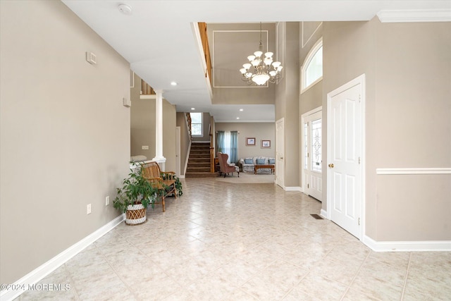 entryway with a chandelier, ornamental molding, and a towering ceiling