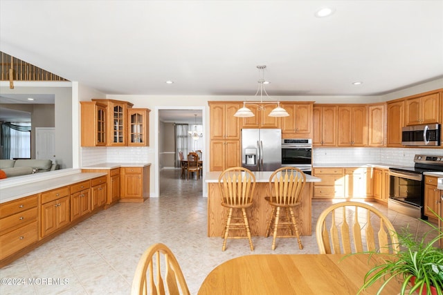 kitchen featuring stainless steel appliances, a kitchen island, backsplash, hanging light fixtures, and a breakfast bar area