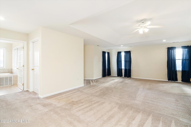 carpeted spare room featuring ceiling fan and a raised ceiling