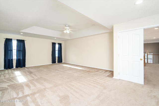 carpeted empty room featuring ceiling fan and a raised ceiling