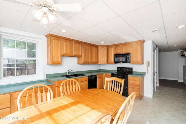 kitchen with light tile patterned floors, sink, black appliances, and a drop ceiling