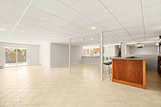 basement with bar area and a drop ceiling