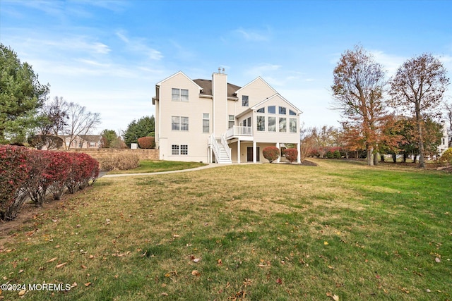 rear view of property featuring a lawn and a sunroom