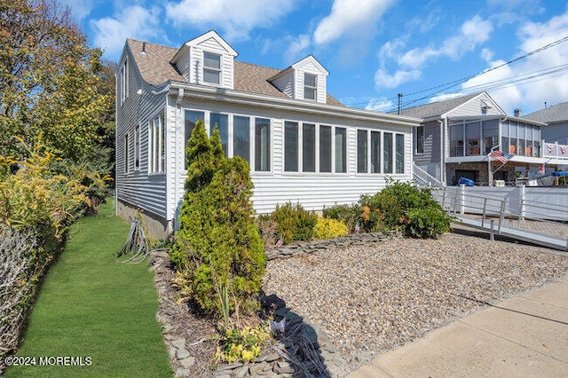 view of front of house featuring a sunroom and a front yard