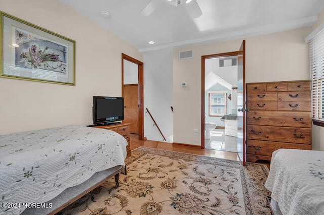 bedroom with connected bathroom, vaulted ceiling, light wood-type flooring, and ceiling fan