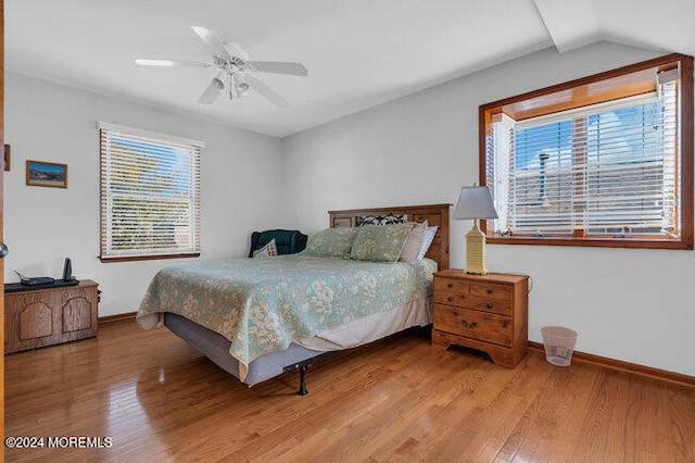 bedroom featuring multiple windows, hardwood / wood-style flooring, lofted ceiling, and ceiling fan