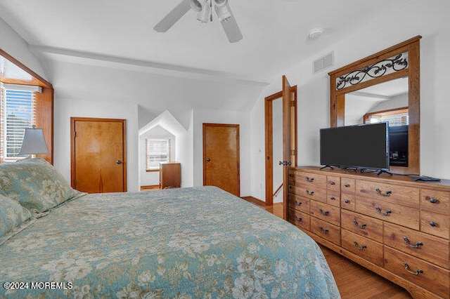 bedroom with vaulted ceiling, multiple windows, wood-type flooring, and ceiling fan