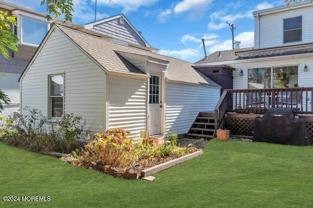 back of property featuring a wooden deck and a lawn