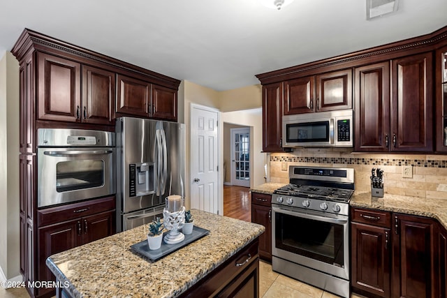 kitchen featuring tasteful backsplash, light tile patterned floors, appliances with stainless steel finishes, and light stone counters