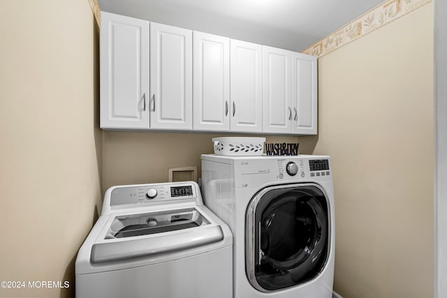 clothes washing area with cabinets and washer and clothes dryer