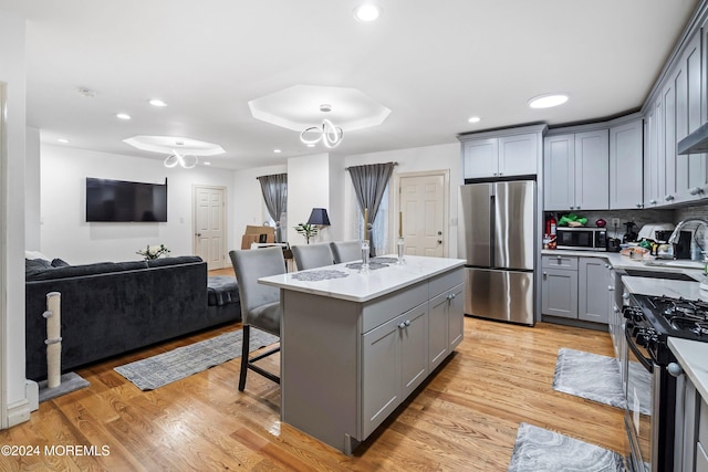 kitchen with tasteful backsplash, appliances with stainless steel finishes, a center island, light hardwood / wood-style floors, and gray cabinets