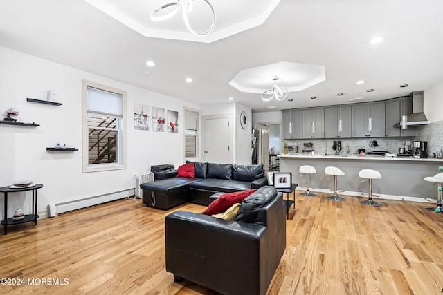 living room featuring a baseboard heating unit, a tray ceiling, and light hardwood / wood-style floors