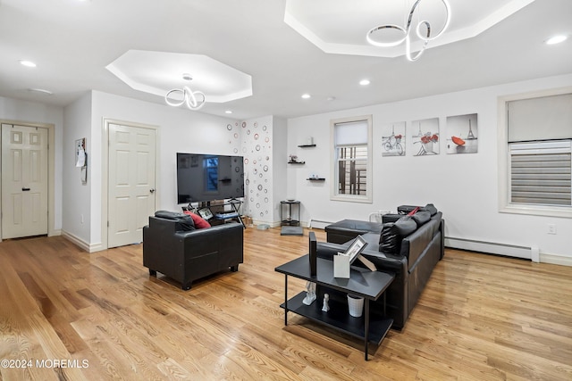 living room with a baseboard heating unit, light hardwood / wood-style floors, and a raised ceiling