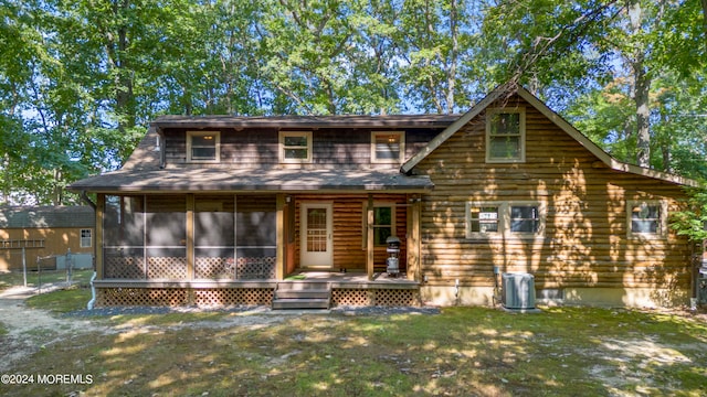 view of front of home featuring a front yard, central AC, and a sunroom