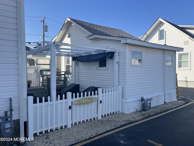 view of front of property with a pergola, fence, and roof with shingles