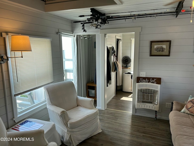 sitting room with wood walls, dark wood-type flooring, and heating unit