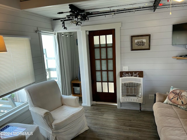 sitting room with dark hardwood / wood-style flooring, heating unit, and wooden walls