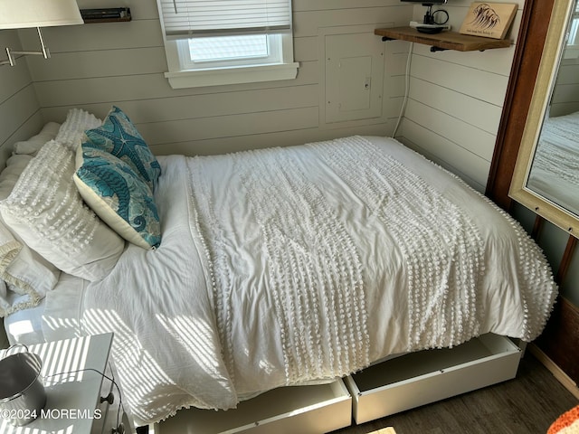 bedroom with dark wood-type flooring and wood walls