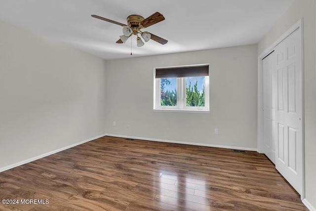 unfurnished bedroom with ceiling fan, a closet, and dark hardwood / wood-style flooring