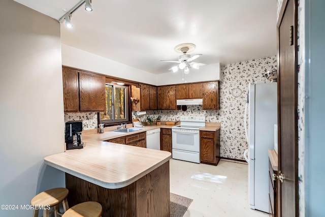 kitchen featuring track lighting, kitchen peninsula, sink, white appliances, and ceiling fan