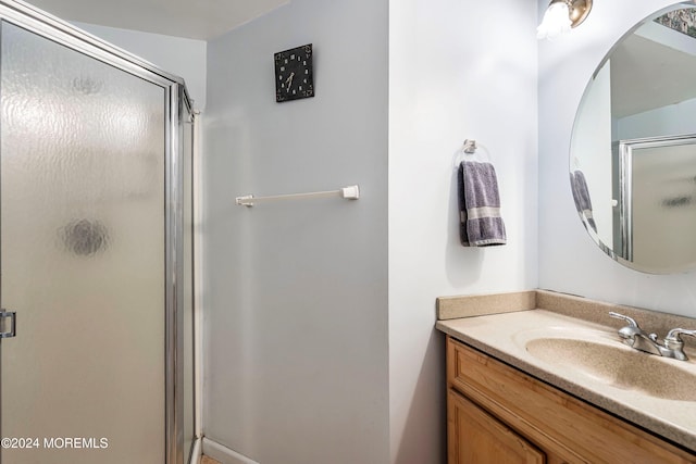 bathroom featuring a shower with door and vanity