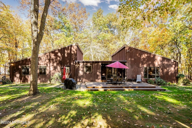 rear view of house featuring a wooden deck and a lawn