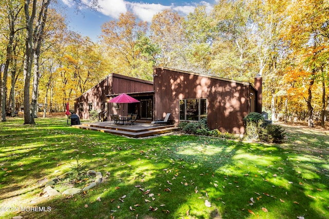 rear view of house featuring a yard and a deck