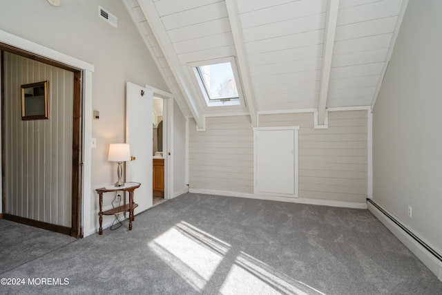 additional living space featuring dark colored carpet, vaulted ceiling with skylight, wood walls, and a baseboard heating unit