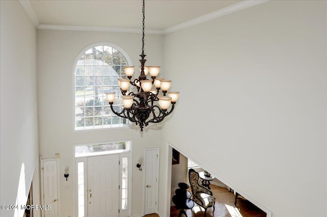 foyer with an inviting chandelier, hardwood / wood-style floors, and ornamental molding